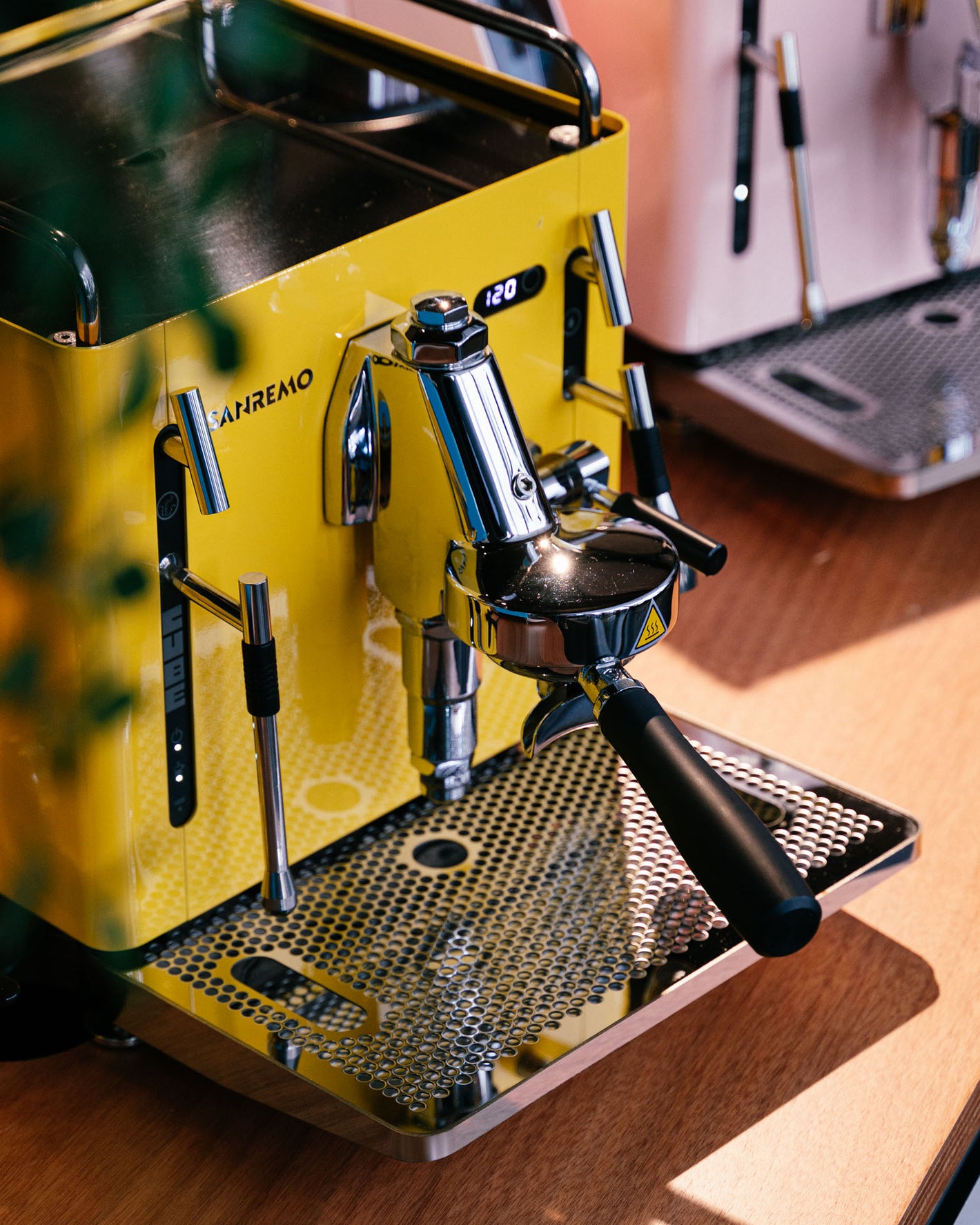 Sanremo CUBE espresso machine in yellow and Sanremo CUBE in pink in the background for home baristas, 3/4 perspective view